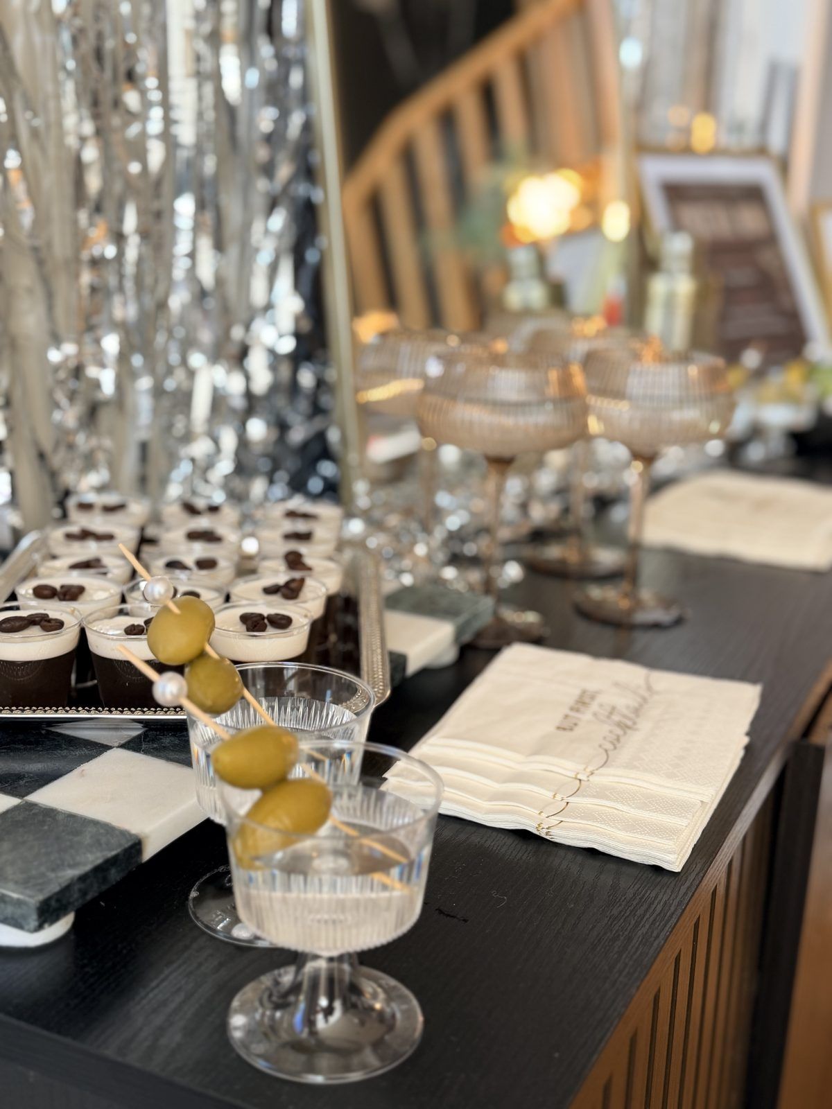Martinis with olive picks beside a tray of espresso martini shots
