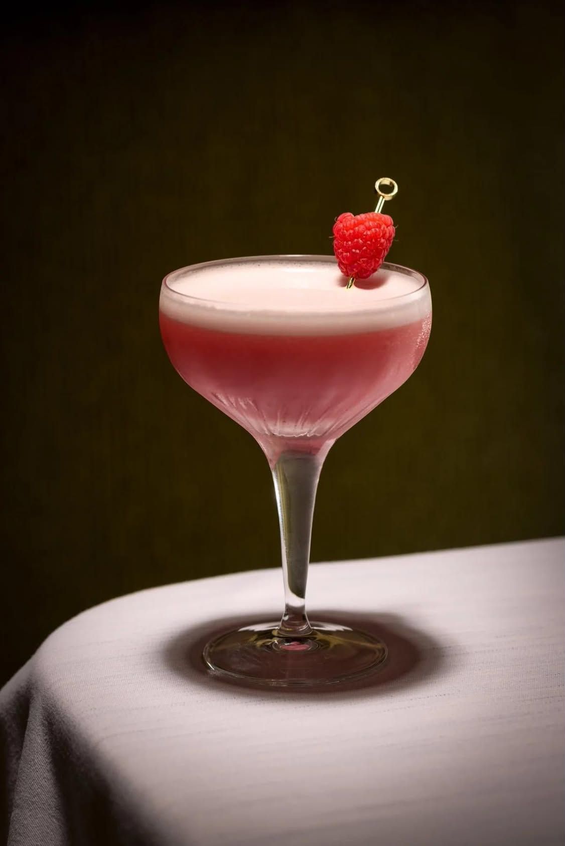 A Clover Club in a coupe with a raspberry on a pick